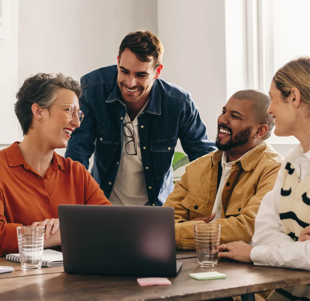 Association members collaborate around a laptop, smiling and engaged in discussion.
